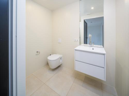 a white bathroom with a toilet and a sink at Harderwold Villa - 228 in Zeewolde