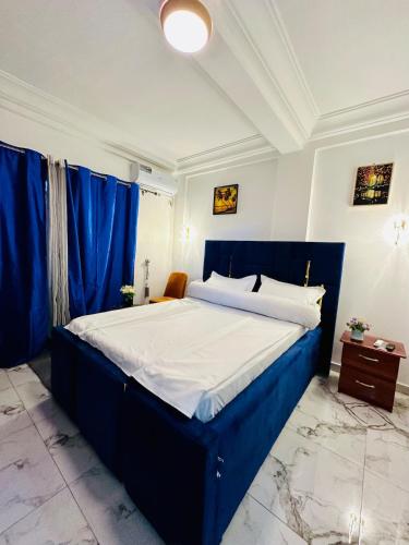 un grande letto blu in una stanza con tende blu di le Cocon Magique a Douala