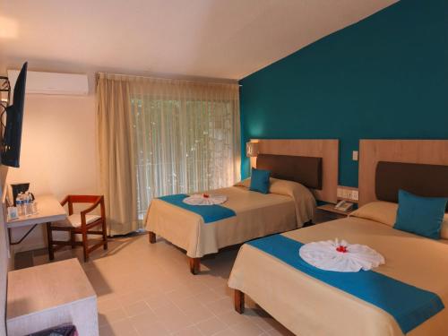 a hotel room with two beds and a table and chairs at Hotel Plaza Palenque in Palenque