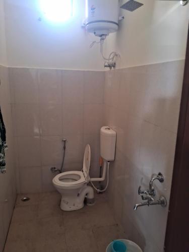 a bathroom with a toilet and a light on the wall at Nilkanth gest hause in Mukteshwar