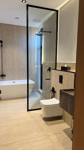 a bathroom with a tub and a toilet and a sink at اصيلة فيلا Asilah Villa in Buraydah