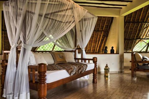 a bedroom with a bed with mosquito netting at Villa Kapungu with private C h e f, XXL pool & garden in Diani Beach