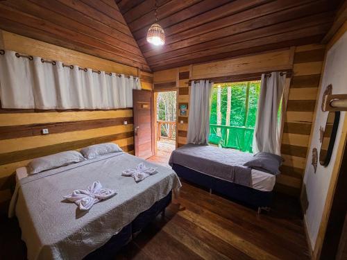two beds in a room with wooden walls at Paroá Amazon Lodge in Manacapuru