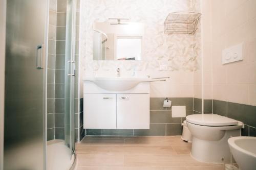 a bathroom with a sink and a toilet and a mirror at Villa Acquamarina, Family apartments with pool - 300 meters from the beach in Santa Maria