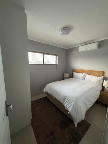 a bedroom with a large white bed and a window at Kheniyas Haven in Nelspruit