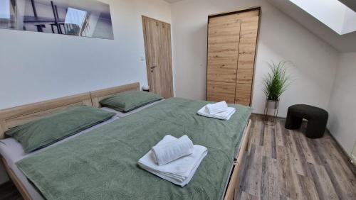 a bedroom with a green bed with towels on it at Apartmán Kovadlina 5 - Kovářov, výhled na Lipno in Frymburk