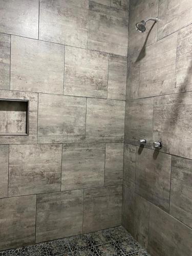 a bathroom with a shower with a stone wall at Costa Ayala - Suites & Bungalows in Los Ayala
