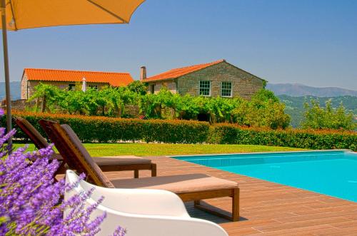 a pool with chairs and an umbrella next to a house at Quinta do Caritel in Vouzela