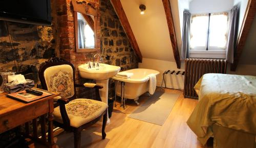 a bathroom with a sink and a tub and a bed at Manoir Sur le Cap in Quebec City
