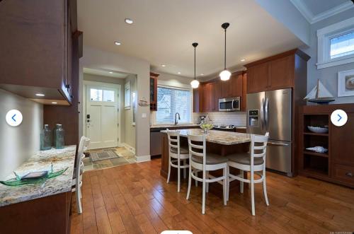 a kitchen with a table and chairs and a refrigerator at Qualicum Landing Coastal Cottage in Qualicum Beach