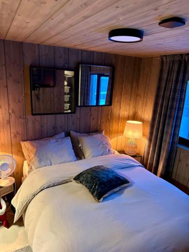 a bedroom with a large white bed with wooden walls at Cabin with sea view in Moen