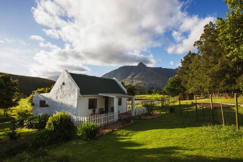 un granero blanco con una montaña al fondo en Hermitage Huisies en Swellendam