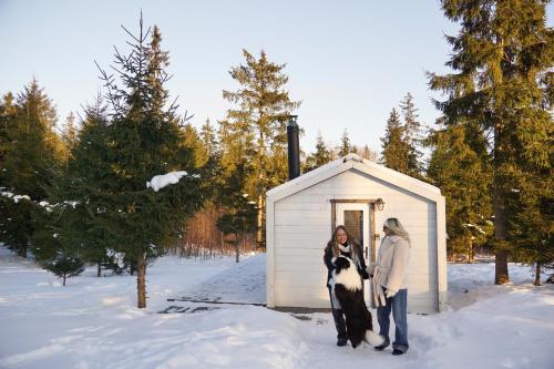 two women standing in front of a small shed at Meža namiņš Upeskrasti in Zosuļi