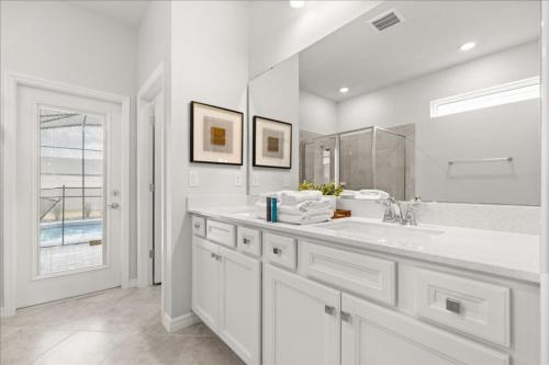 a white bathroom with a sink and a mirror at 16159Coastal in Clermont