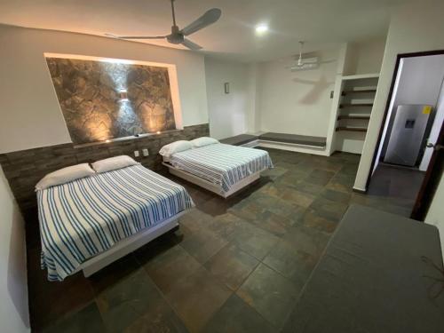 a room with two beds and a ceiling fan at Costa Ayala - Suites & Bungalows in Los Ayala