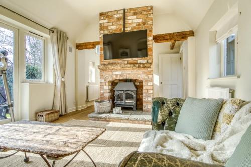 a living room with a stone fireplace with a tv at Gleanings Cottage in Bredon