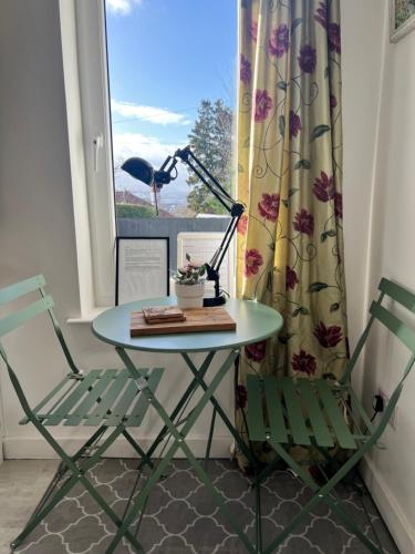 a table with a lamp and two chairs in front of a window at Self-contained ground level cottage with hill view in Edinburgh