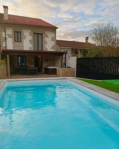 a large blue swimming pool in front of a house at A Casa da aldea de Iria in Padrón