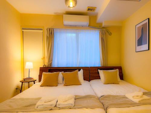 a bedroom with two beds with yellow walls and a window at Odori 601 Max 7 guests Odori Park 4m Tram 2m Subway 4m in Ōdōri