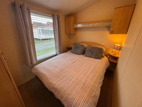 a bed in a small room with a window at 8 berth pet friendly caravan, Penrhyn Bay, Llandudno in Llandudno