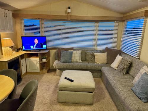 a living room with a couch and a television at 8 berth pet friendly caravan, Penrhyn Bay, Llandudno in Llandudno