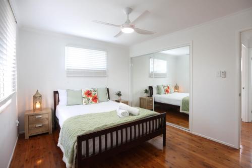 a bedroom with a bed and a mirror at Enchanted Garden, 3 bedrooms in Sandstone Point