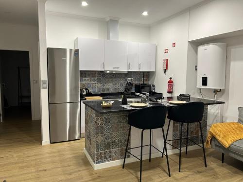 a kitchen with a refrigerator and a counter with bar stools at Frades house in Câmara de Lobos