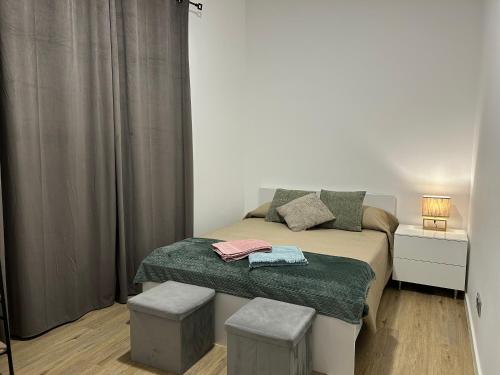 a small bedroom with a bed and two stools at Frades house in Câmara de Lobos