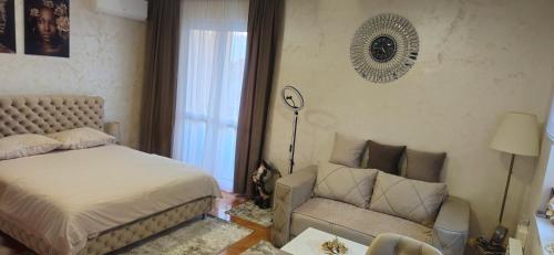 a bedroom with a bed and a couch and a chair at Apartman Tajna in Sremčica