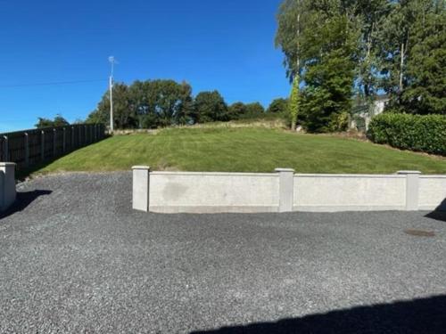 a white stone wall in front of a grassy hill at 5 Bedroom Home Monaghan Town in Monaghan