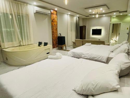 two beds in a room with a tub and a bedroom at Golden mask pyramids inn in Cairo