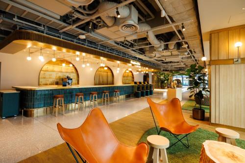 a lobby with orange chairs and a bar at HOTEL METROPOLITAN OIMACHI TRACKS Tokyo in Tokyo