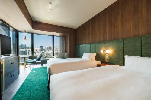 two beds in a hotel room with a view at HOTEL METROPOLITAN OIMACHI TRACKS Tokyo in Tokyo