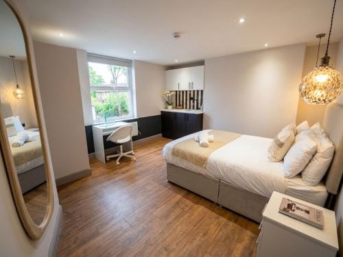 a bedroom with a bed and a desk and a mirror at Clapton Station Luxury Studios near Central London in London