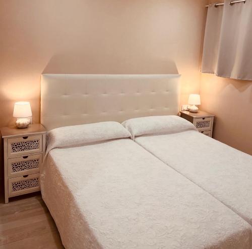 a bedroom with a white bed and two night stands at Olimpus Apart Leasure in Costa de Adeje