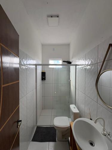 a white bathroom with a toilet and a sink at Varanda das Dunas in Santo Amaro