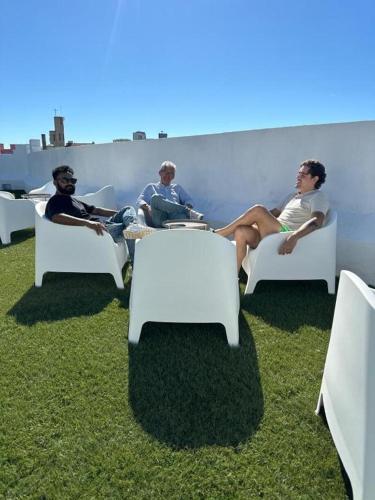 a group of people sitting in white chairs on the grass at Samps Hostel in Lisbon