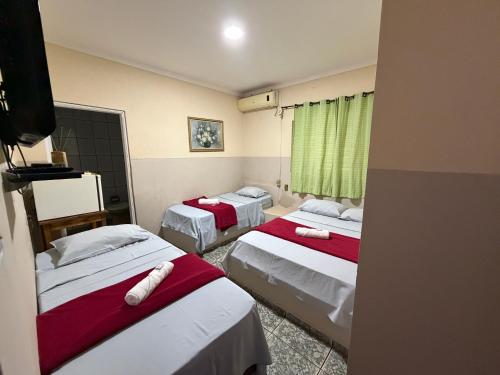 two beds in a room with green curtains at Ferrari's Hotell in Miguelópolis
