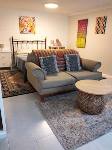 a living room with a couch and a table and a bed at Guest suite-2 beds,private entry, bathroom & laundry in Wollongong