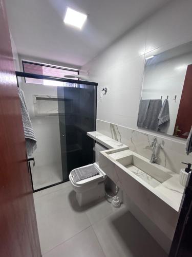 a bathroom with a toilet and a sink and a mirror at Refúgio em Intermares, 250m do Mar com piscina in Cabedelo