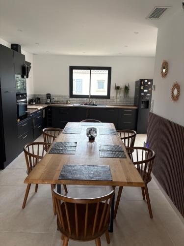 Maison- Aude في Cuxac-dʼAude: مطبخ كبير مزود بطاولة وكراسي خشبية