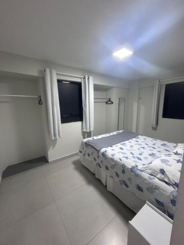 a white bedroom with a bed and two windows at Refúgio em Intermares, 250m do Mar com piscina in Cabedelo