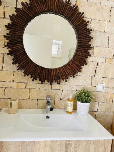 a bathroom sink with a mirror on a brick wall at Largo de Santa Ana in Cadaval