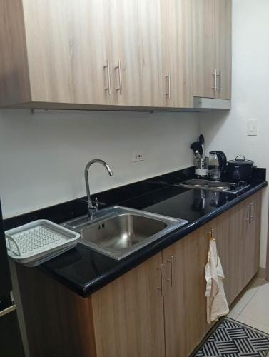 eine Küche mit Edelstahlspüle und Holzschränken in der Unterkunft JAS Staycation in Manila