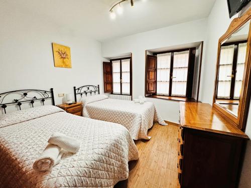 a bedroom with two beds and two windows at Apartamentos Rurales LLeguera in Llanes