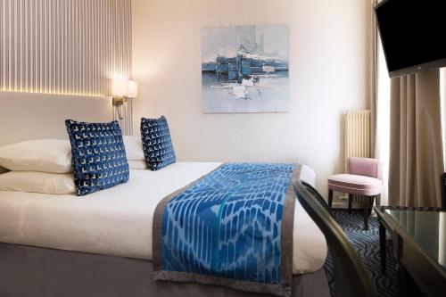 a hotel room with a bed with blue and white pillows at Hôtel Victor Hugo Paris Kléber in Paris