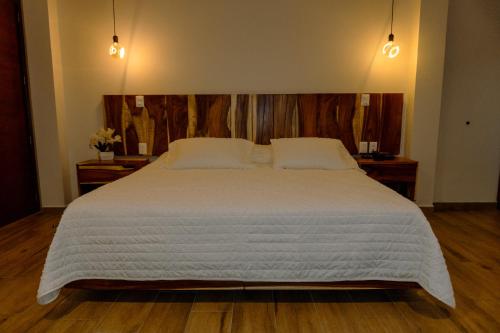 a bedroom with a large white bed with wooden floors at Hotel Tres Reinas in Xicotepec de Juárez