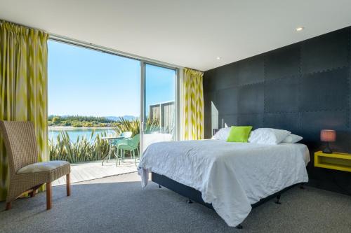 a bedroom with a bed and a balcony with a view at Mapua Wharfside Apartments in Mapua