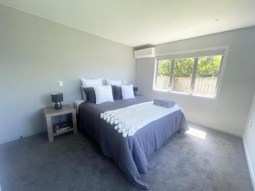 a bedroom with a large bed and a window at Beachside Bliss - Modern Luxury in Napier