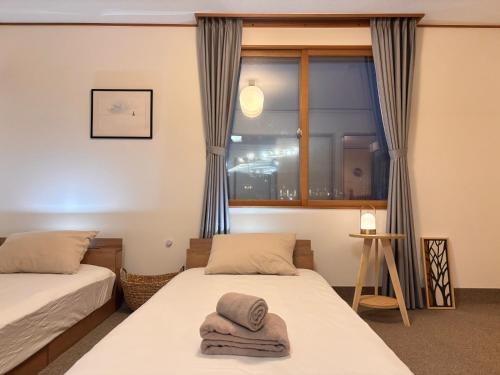 two beds in a room with a window at Snoa Kitanomine - スノア キタノミネ - in Furano